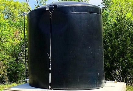 A large black water tank is sitting on top of a concrete platform.