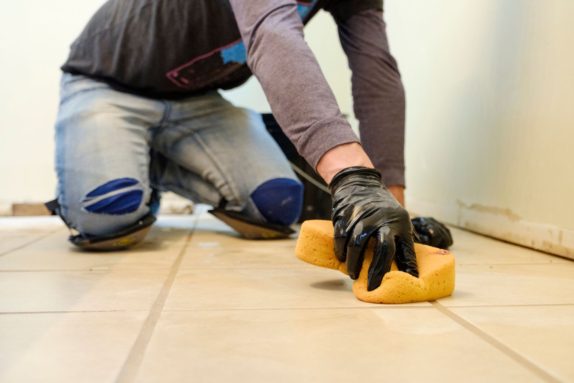 A man in gloves cleans tile 