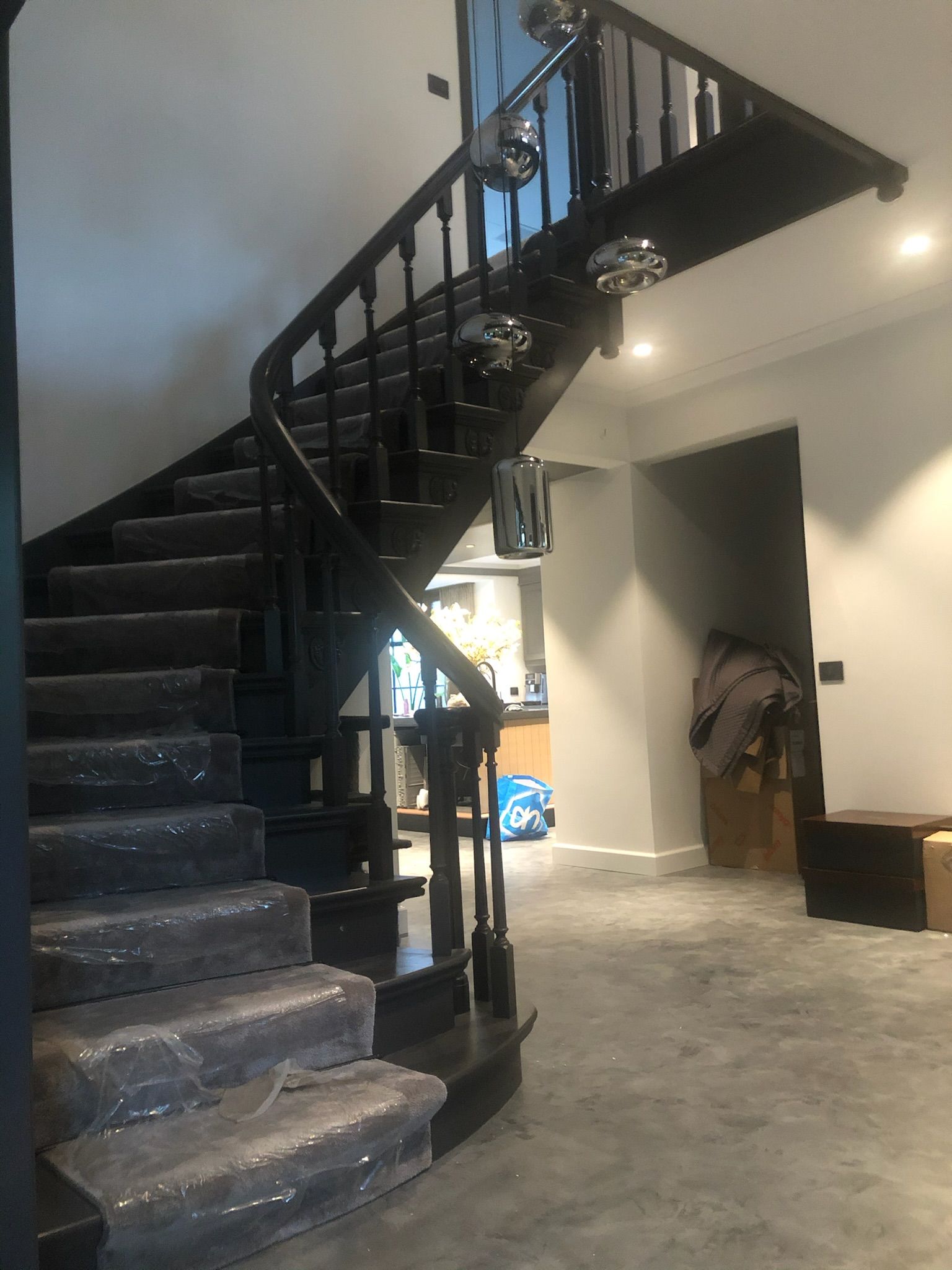 Zwarte trap met plasticfolie op de treden, die naar een overloop leidt.