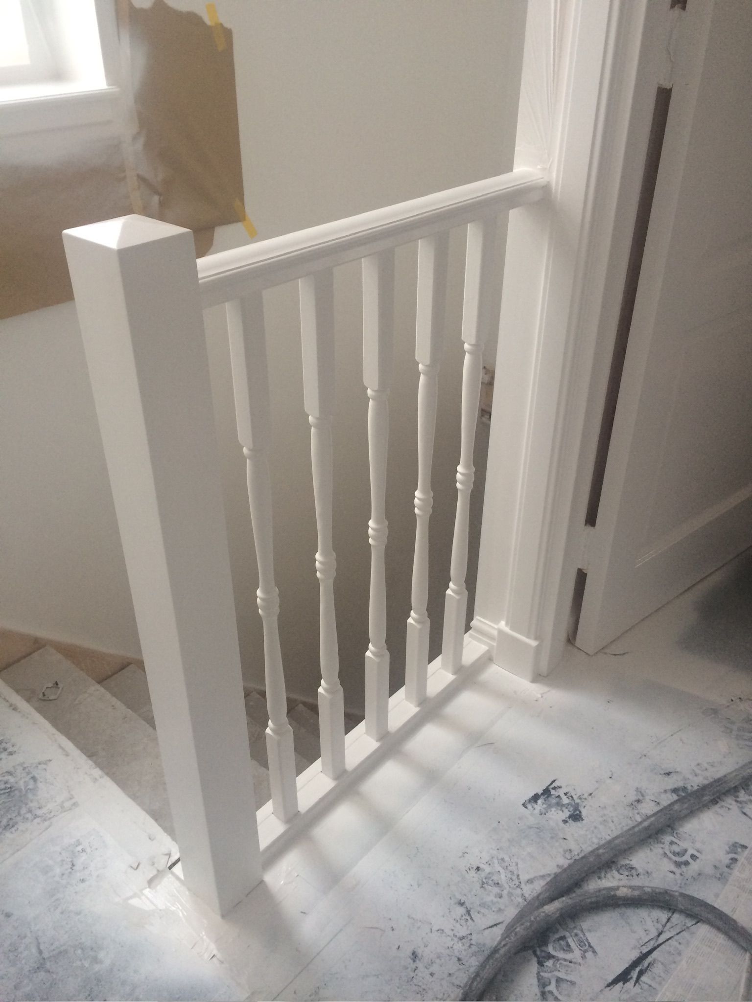 Witgeschilderde trapleuning met spijlen, die naar beneden leidt.