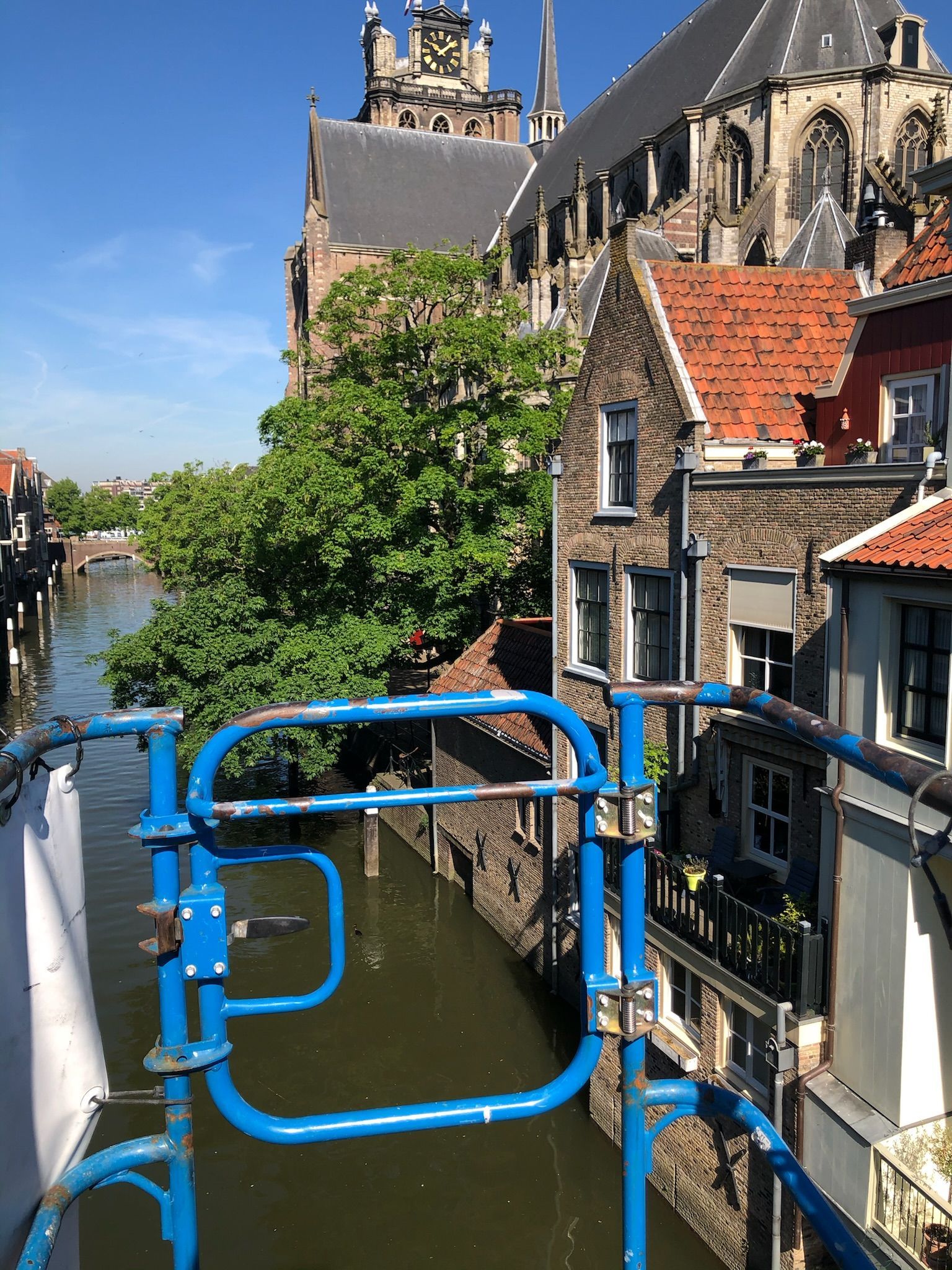 Blauwe steigers kijken uit over een kanaal in een Europese stad, met zichtbare gebouwen en een kerk.