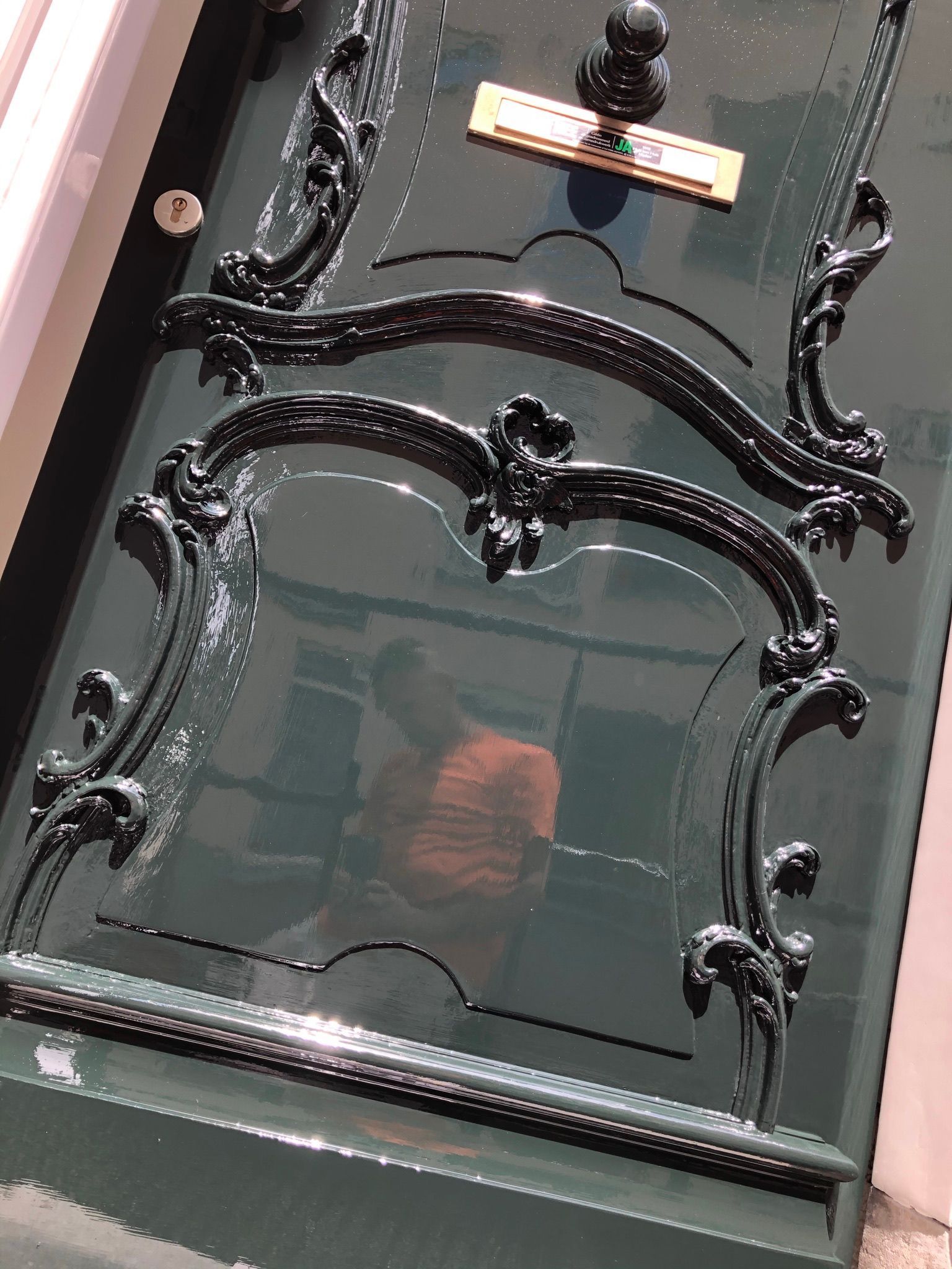 Groene houten deur met sierlijk zwart ijzerwerk.