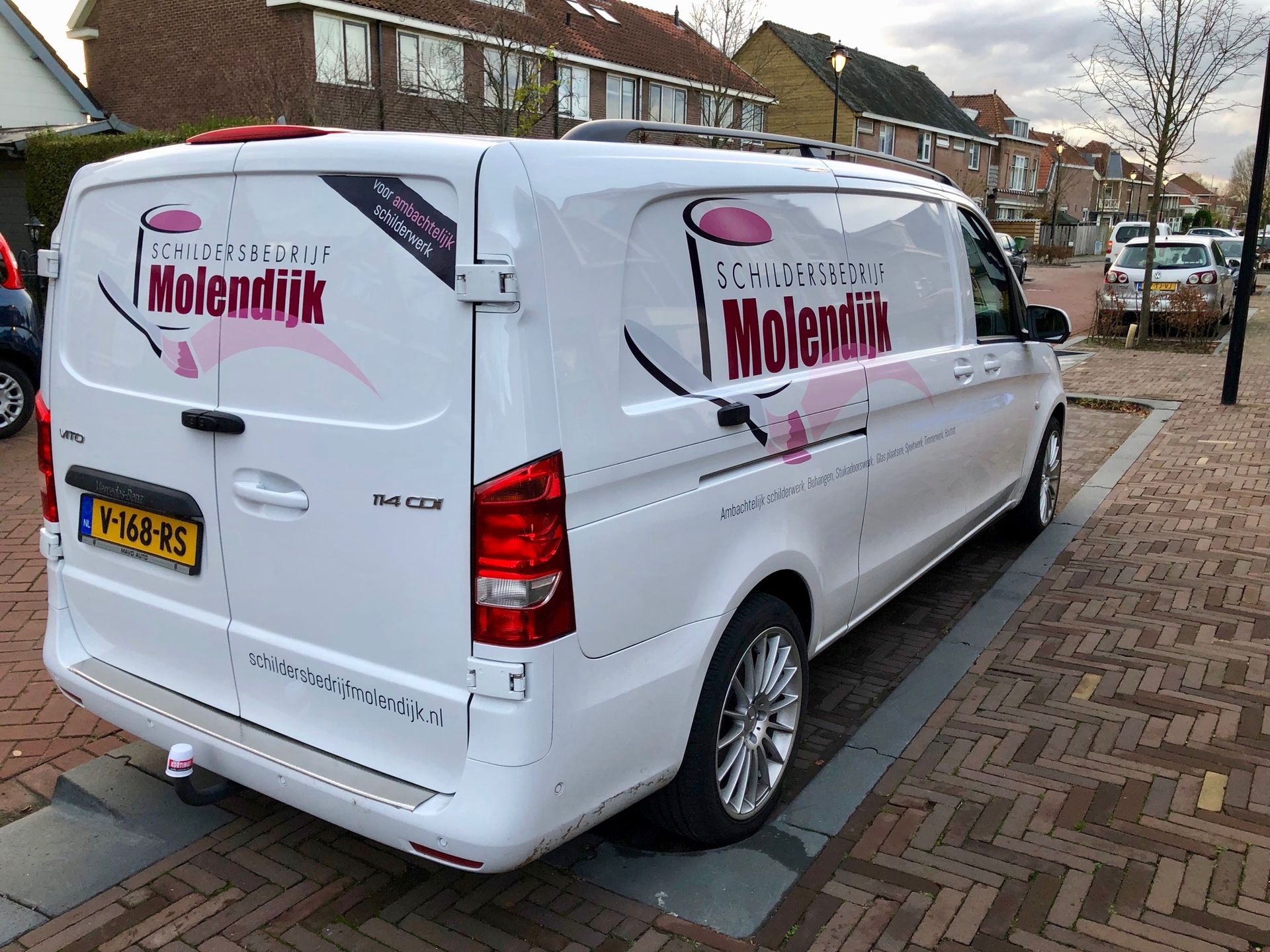 White van parked on a brick sidewalk; 