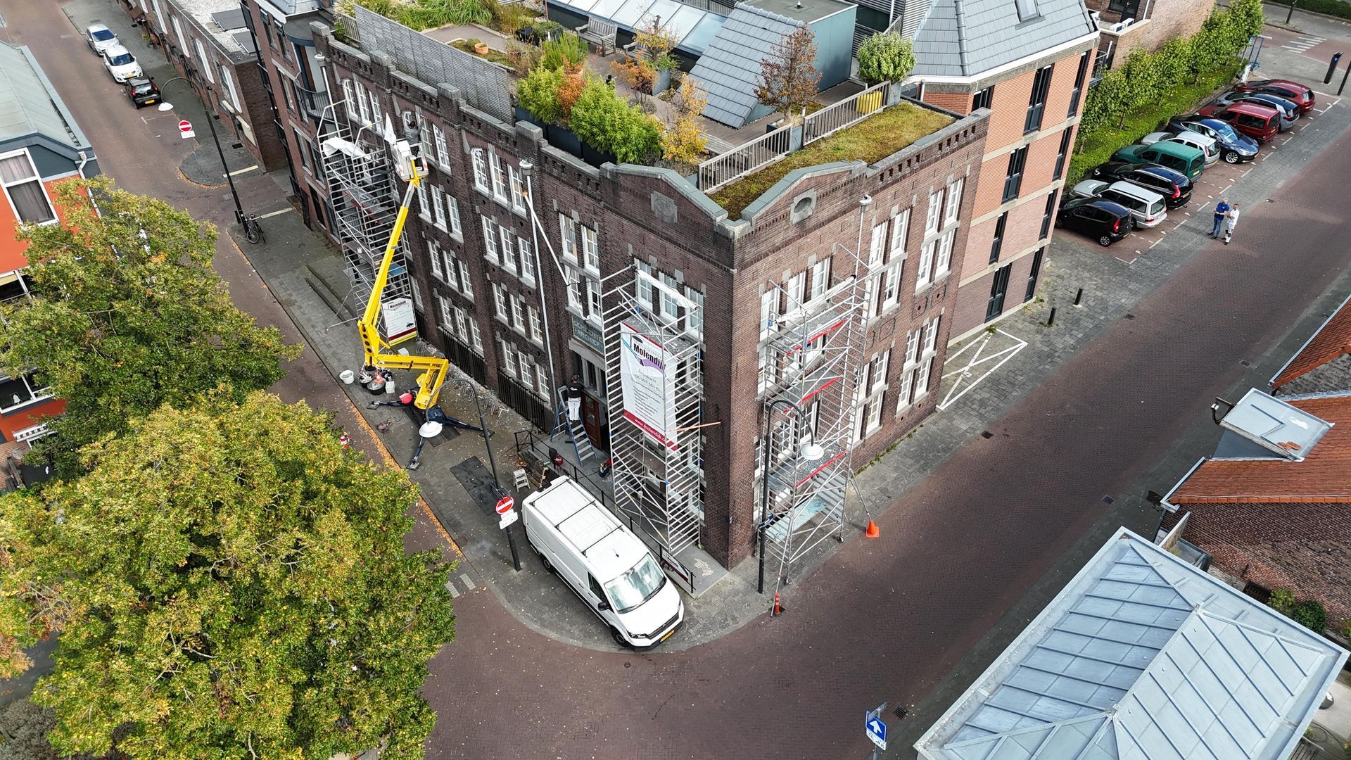 Groene voordeur met decoratief zwart traliewerk, geflankeerd door bakstenen en een bloempothouder.