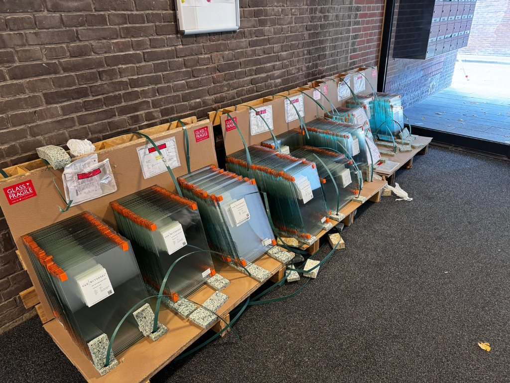 Gebouwen op straat, steigers ernaast. Bruine en witte gevels onder een bewolkte lucht.