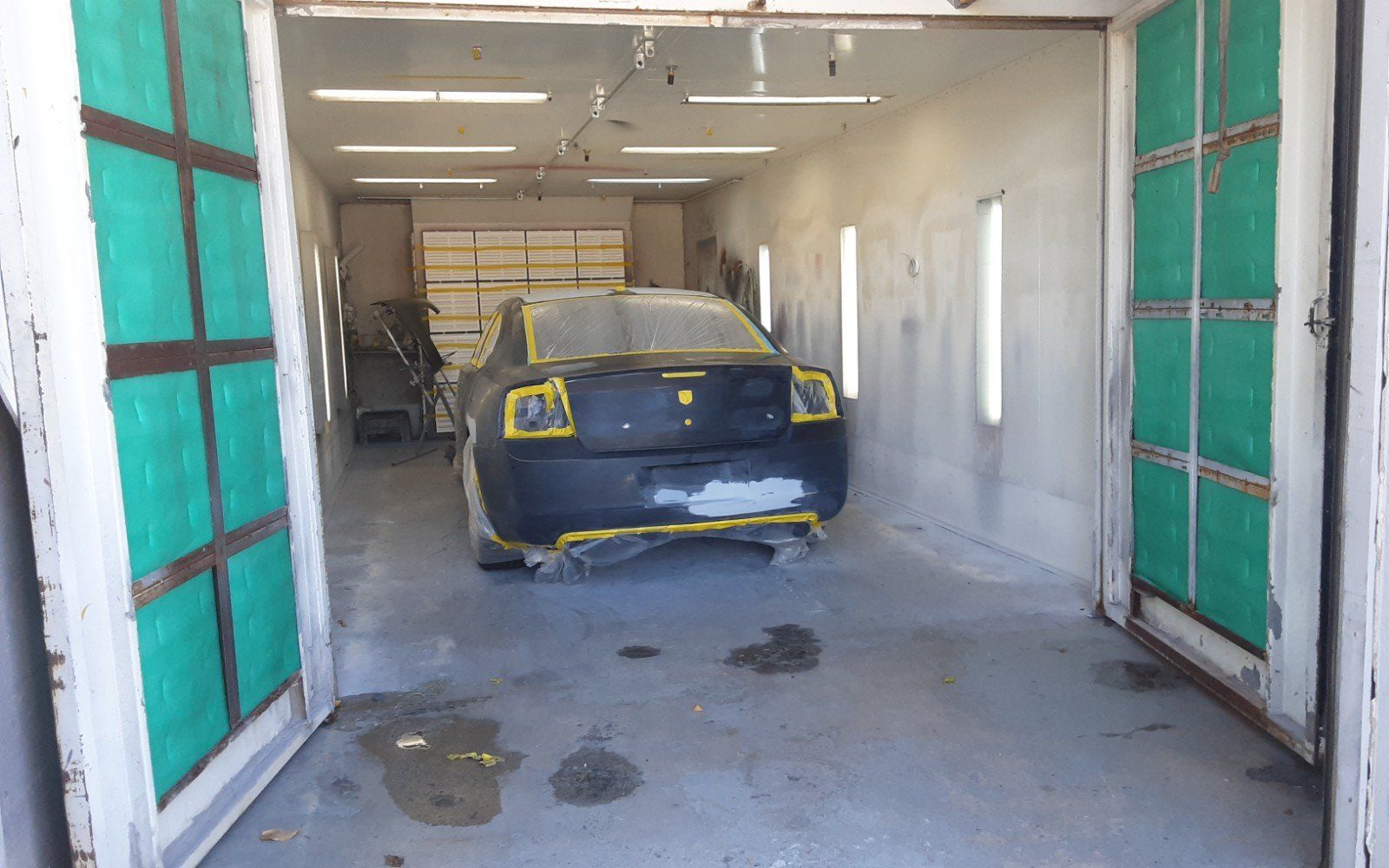 A car is sitting in a paint booth in a garage.