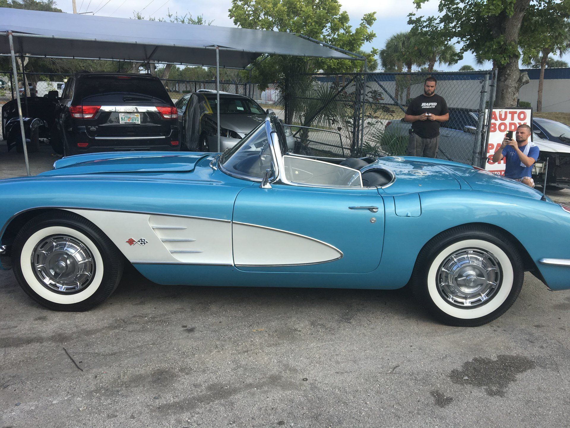 A blue and white sports car is parked in a parking lot.