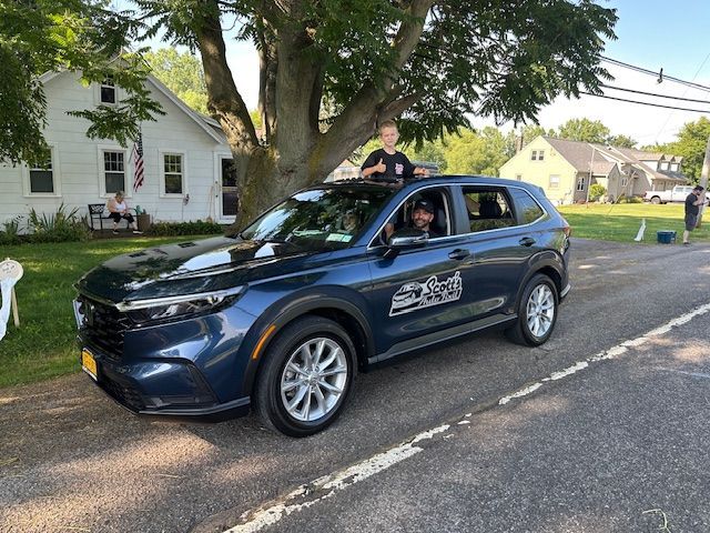 A group of people are sitting at a table with plates of food and a bottle of wine.