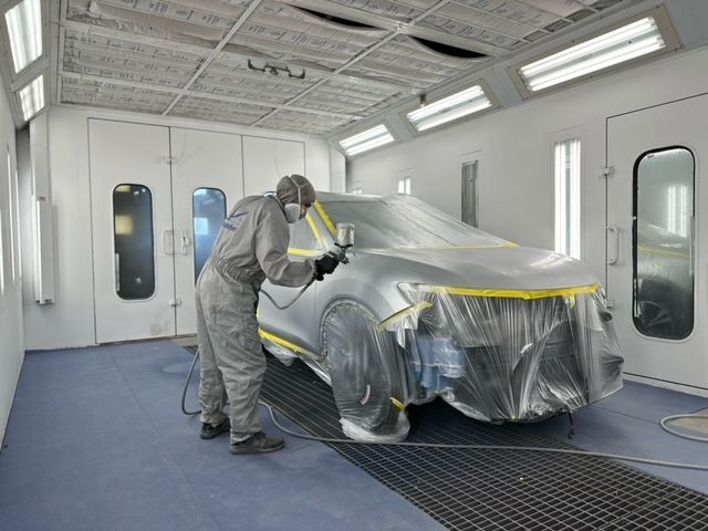 A man is spray painting a car in a paint booth.