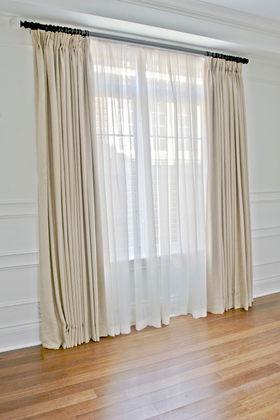 A living room with white curtains and a wooden floor.
