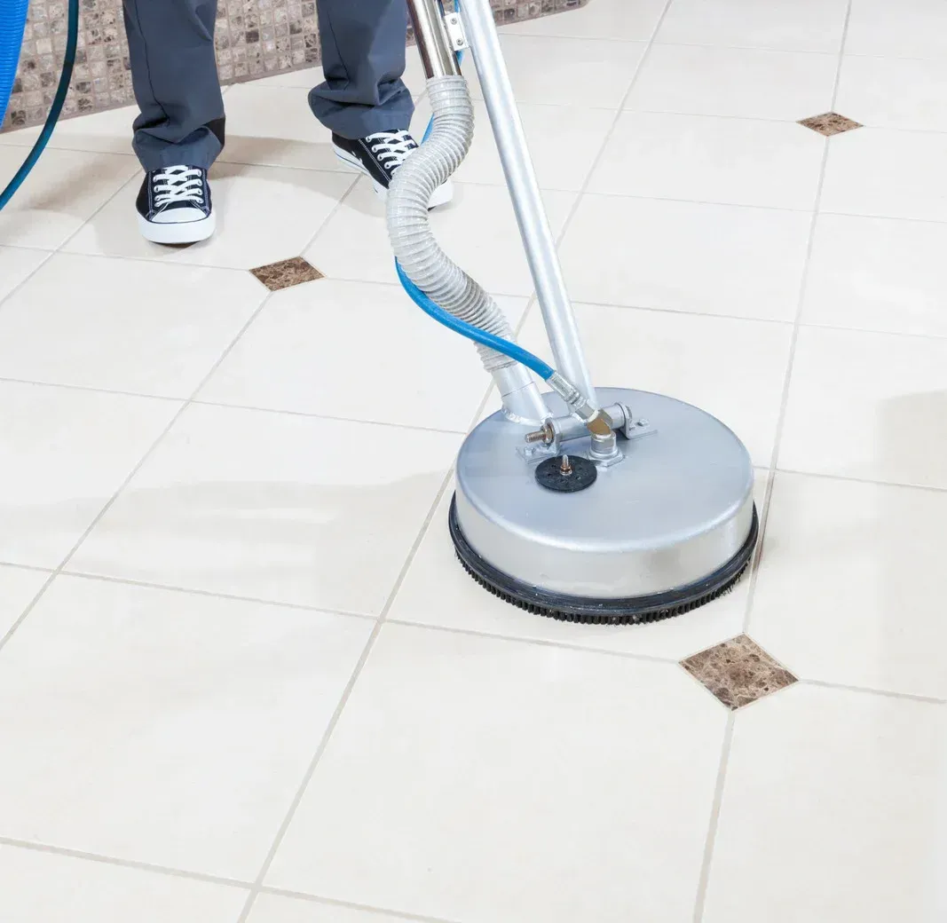 A woman is cleaning a couch with a vacuum cleaner.