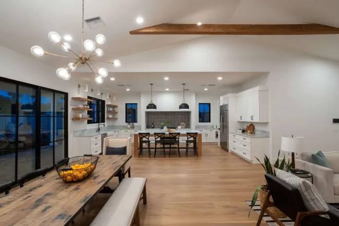 Spacious open-concept kitchen and dining area with wooden floors, white cabinets, and a large dining table.