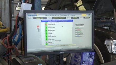 A dell computer monitor is sitting in front of a car.