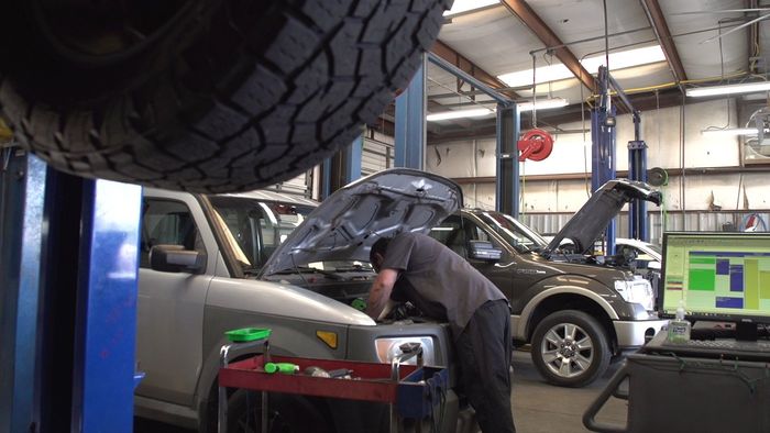 A man is working on a truck in a garage.
