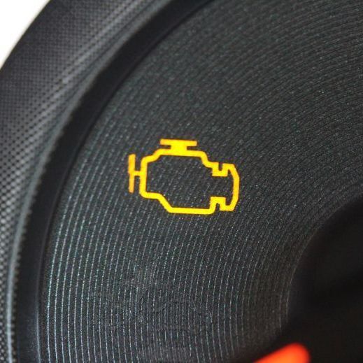 A close up of a car dashboard with a yellow engine icon