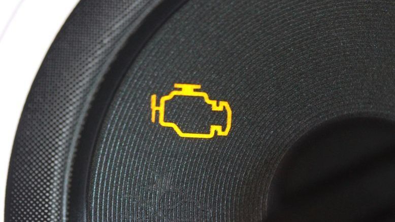 A yellow engine light is on the dashboard of a car.