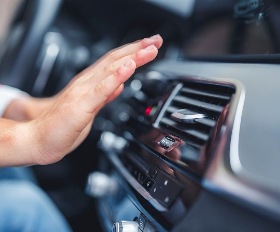 A person is adjusting the air conditioner in a car.