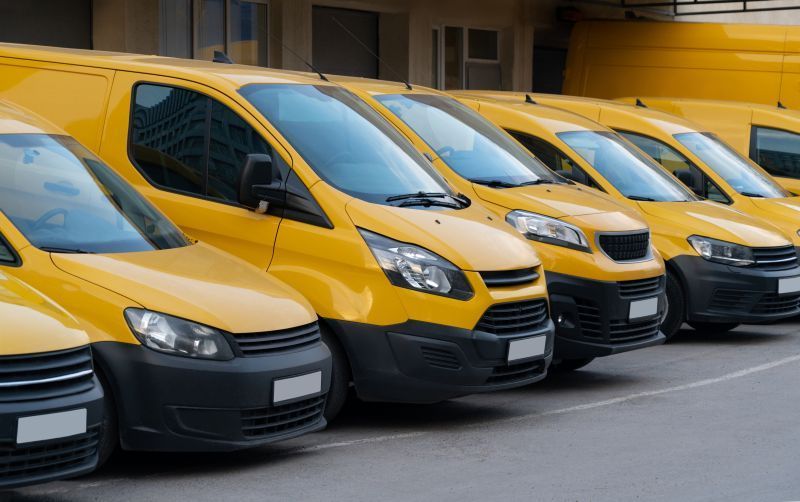 A row of yellow vans are parked in a parking lot.