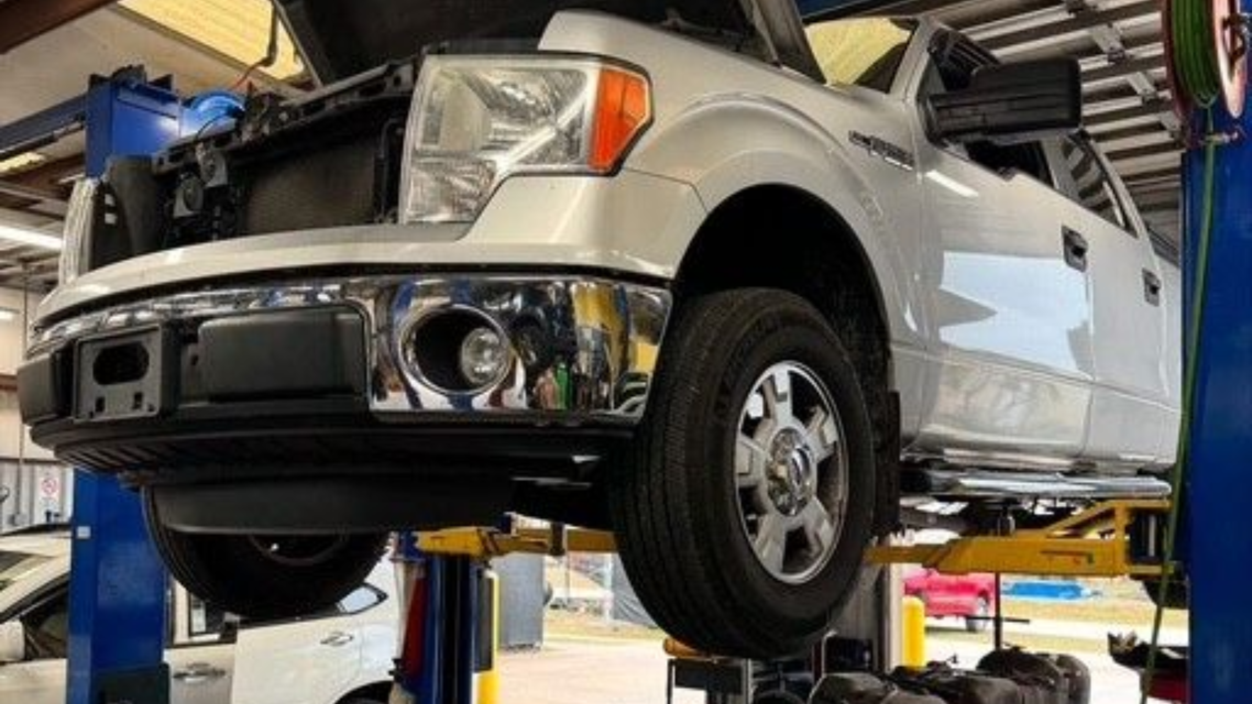 Silver Ford F-150 truck raised on a lift in a repair shop for maintenance.