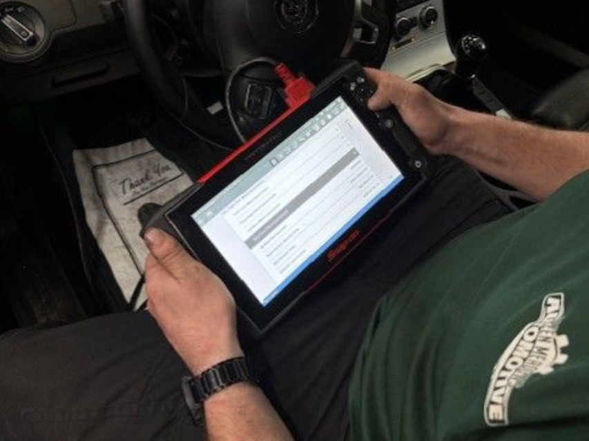 Person using a diagnostic tablet in a car, checking engine data.