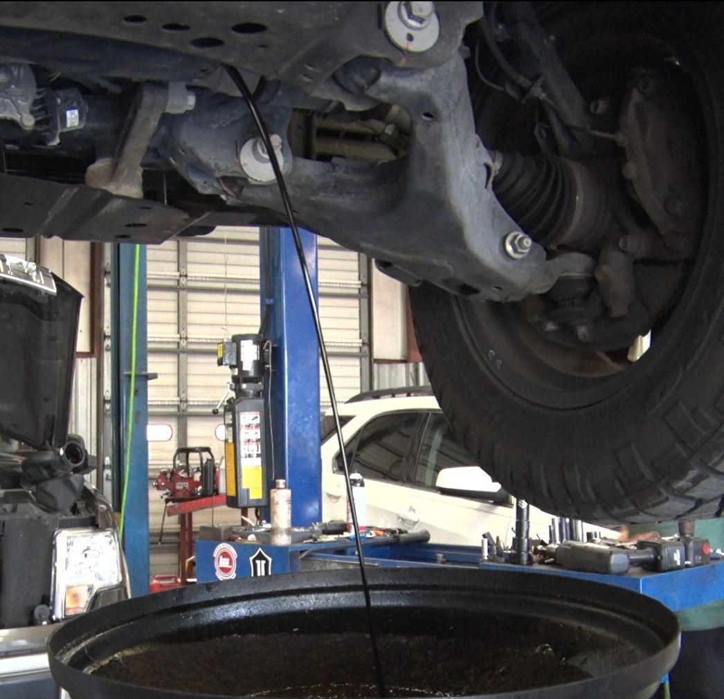 A bucket of oil is being poured under a car