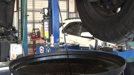 A bucket of oil is being poured under a car