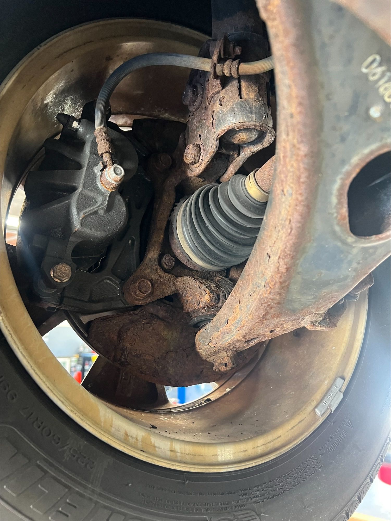 Close-up of a car wheel well showing the brake rotor, suspension, and CV axle boot.
