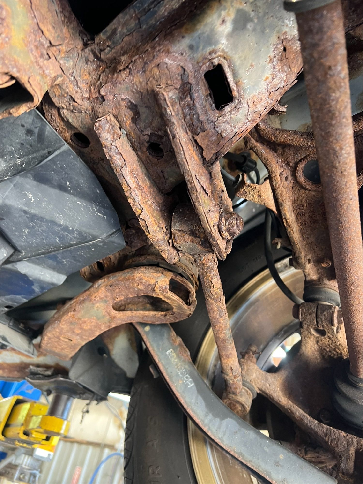 Rusty undercarriage of a vehicle with suspension parts and wheel hub visible