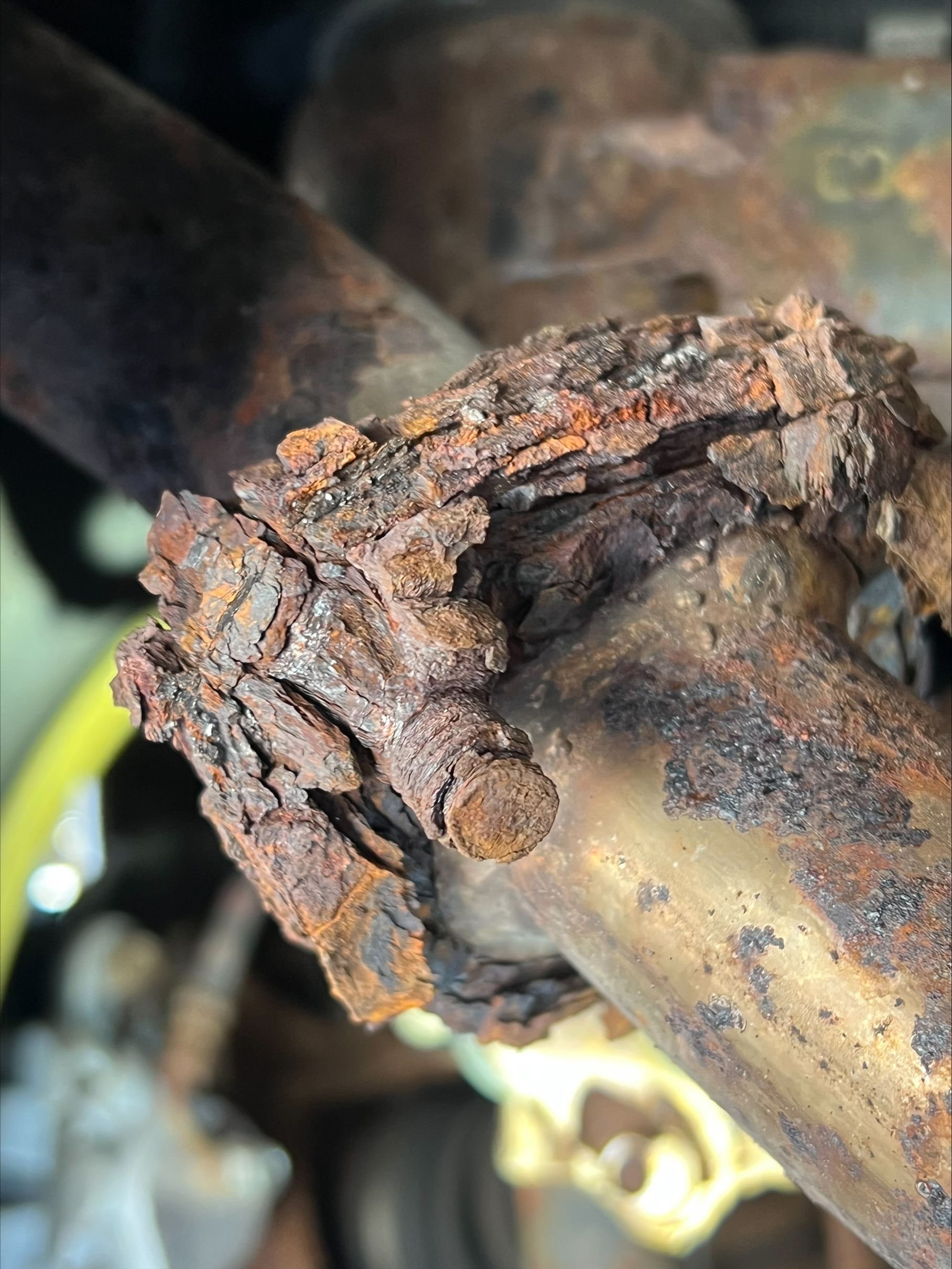 Rust-covered metal pipe joint with severe corrosion and flaking buildup