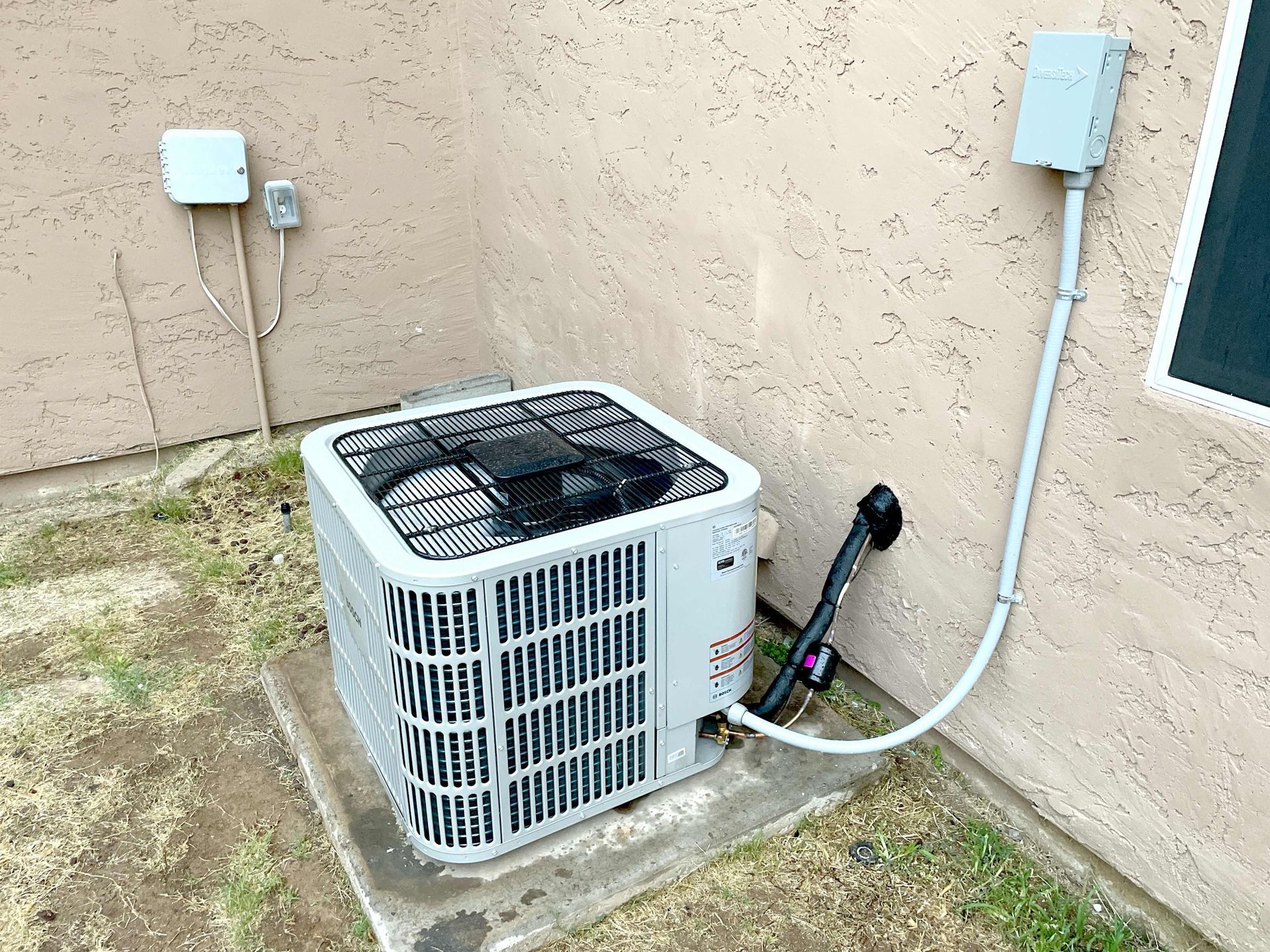 A white air conditioner is sitting on the side of a building.
