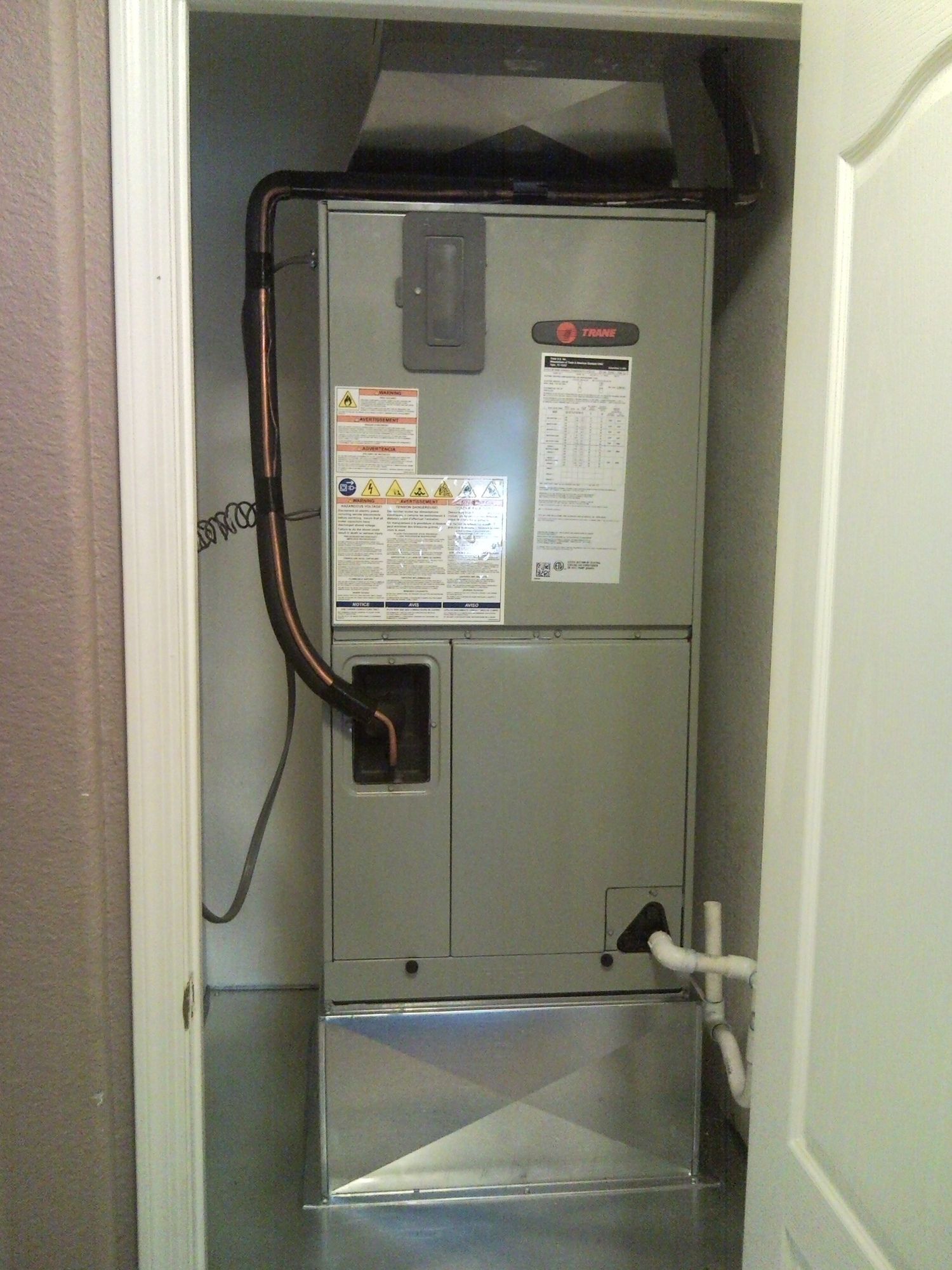 An air conditioner is sitting in a closet next to a door