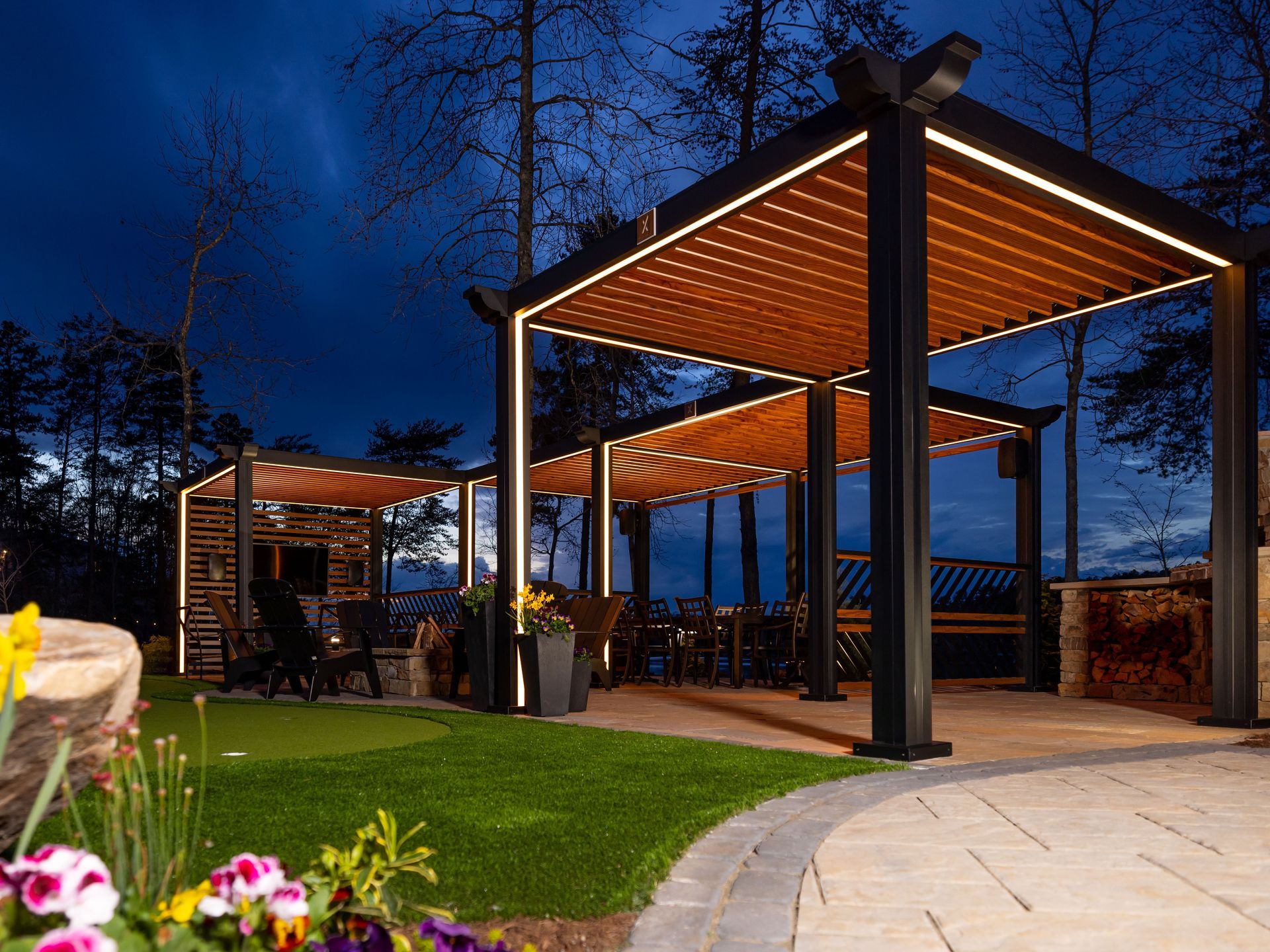 A pergola is lit up at night in a backyard.