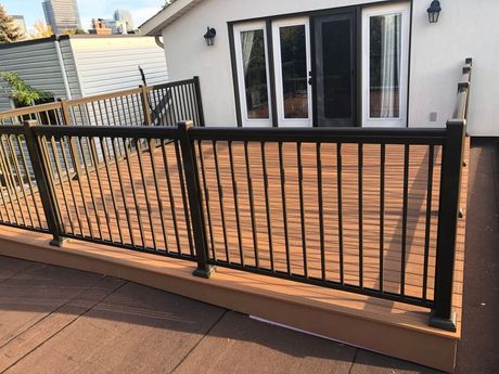 A wooden deck with stairs leading up to it in front of a house.