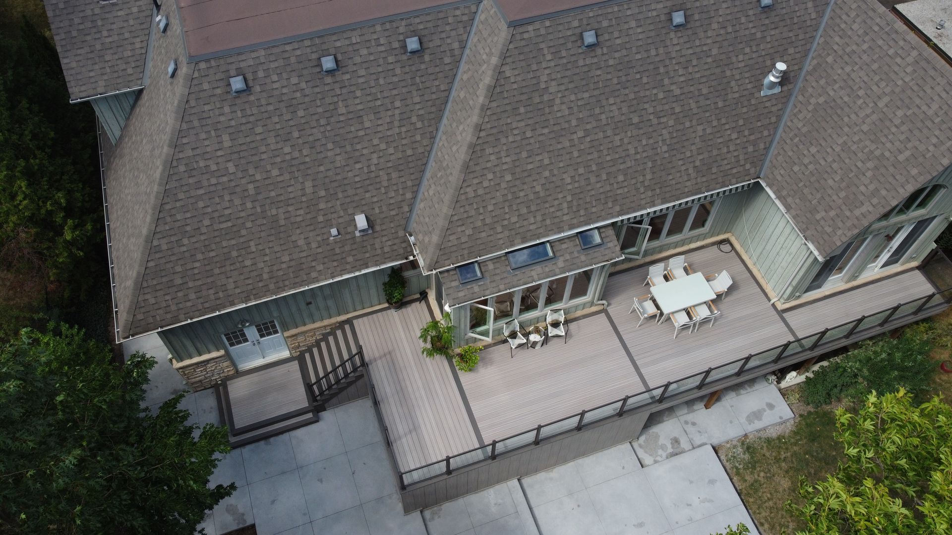 Aerial view of expansive backyard deck with two dining sets.