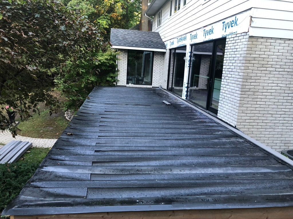 A wooden deck is sitting in front of a brick house.