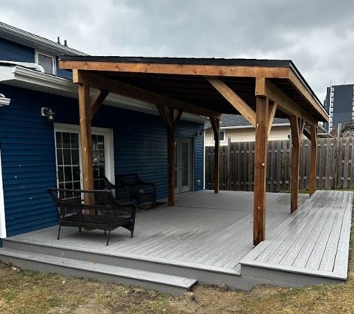 Wooden patio cover attached to a blue house with gray deck and seating.
