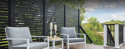 Outdoor patio with black privacy fence, white furniture, candles, and a scenic view.