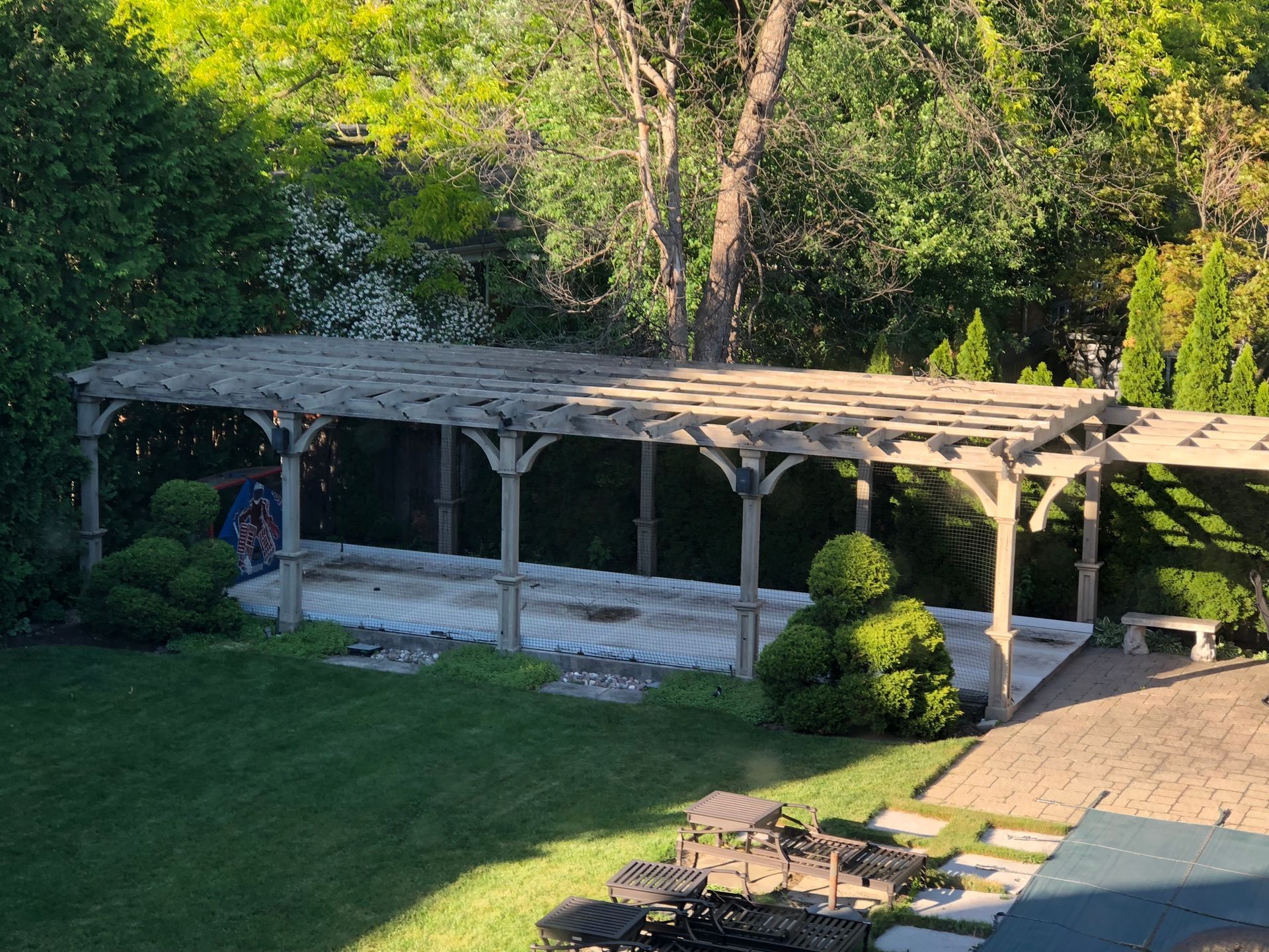 A wooden pergola is sitting in the middle of a lush green yard.