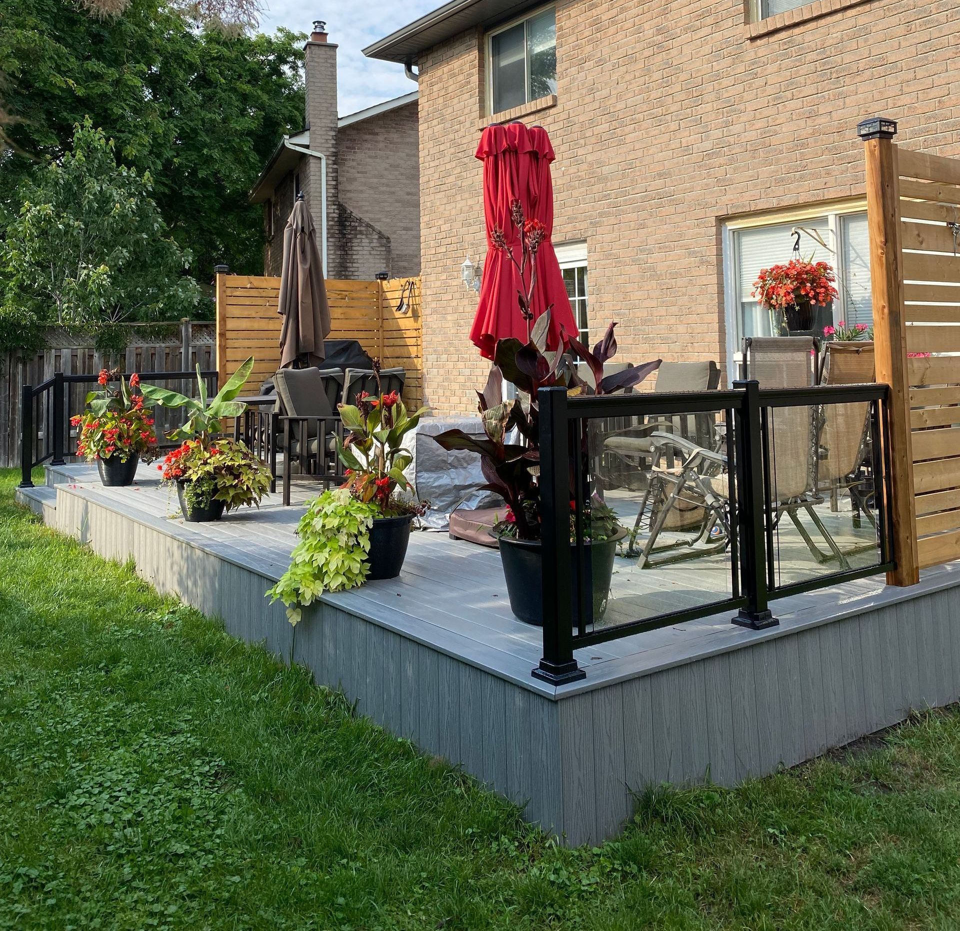 A patio with a red umbrella and potted plants