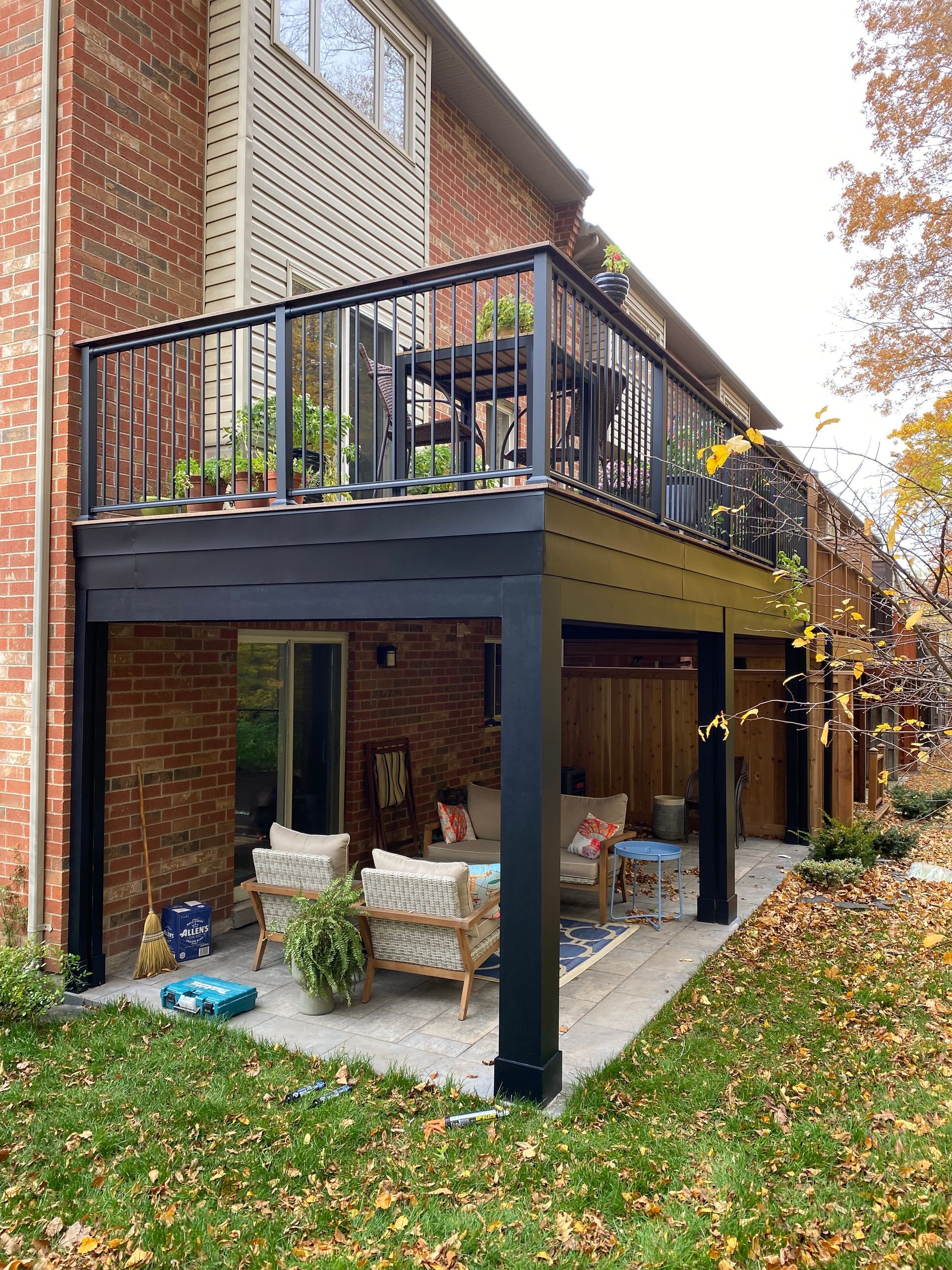 A large deck with a black railing is sitting on the side of a brick house.