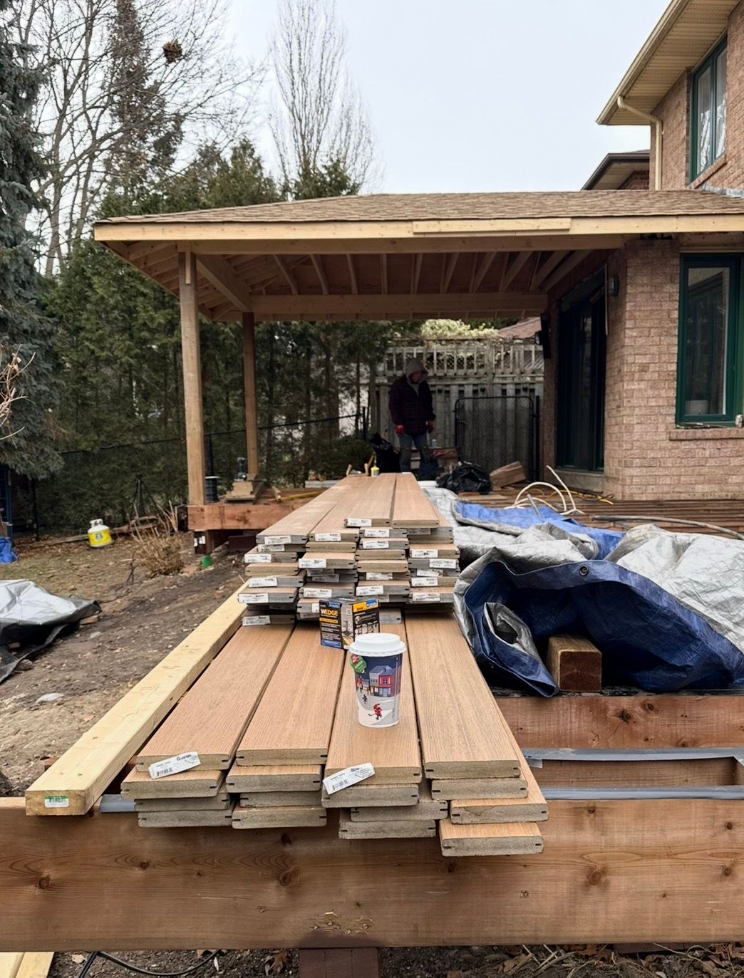 Brown composite deck with black railing and glass balusters; view of garden, fountain, and lawn.