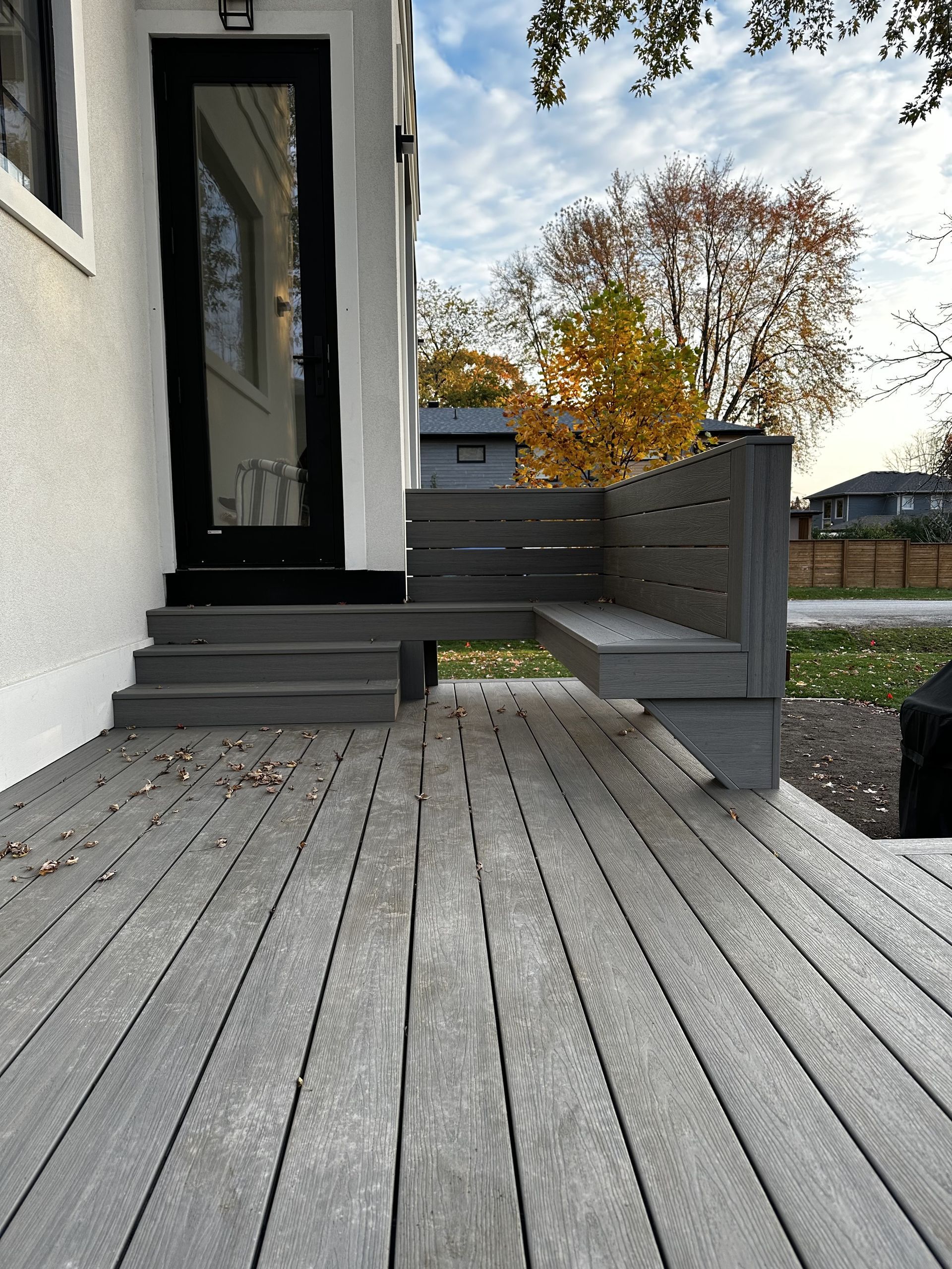 A wooden deck with a bench in front of a house