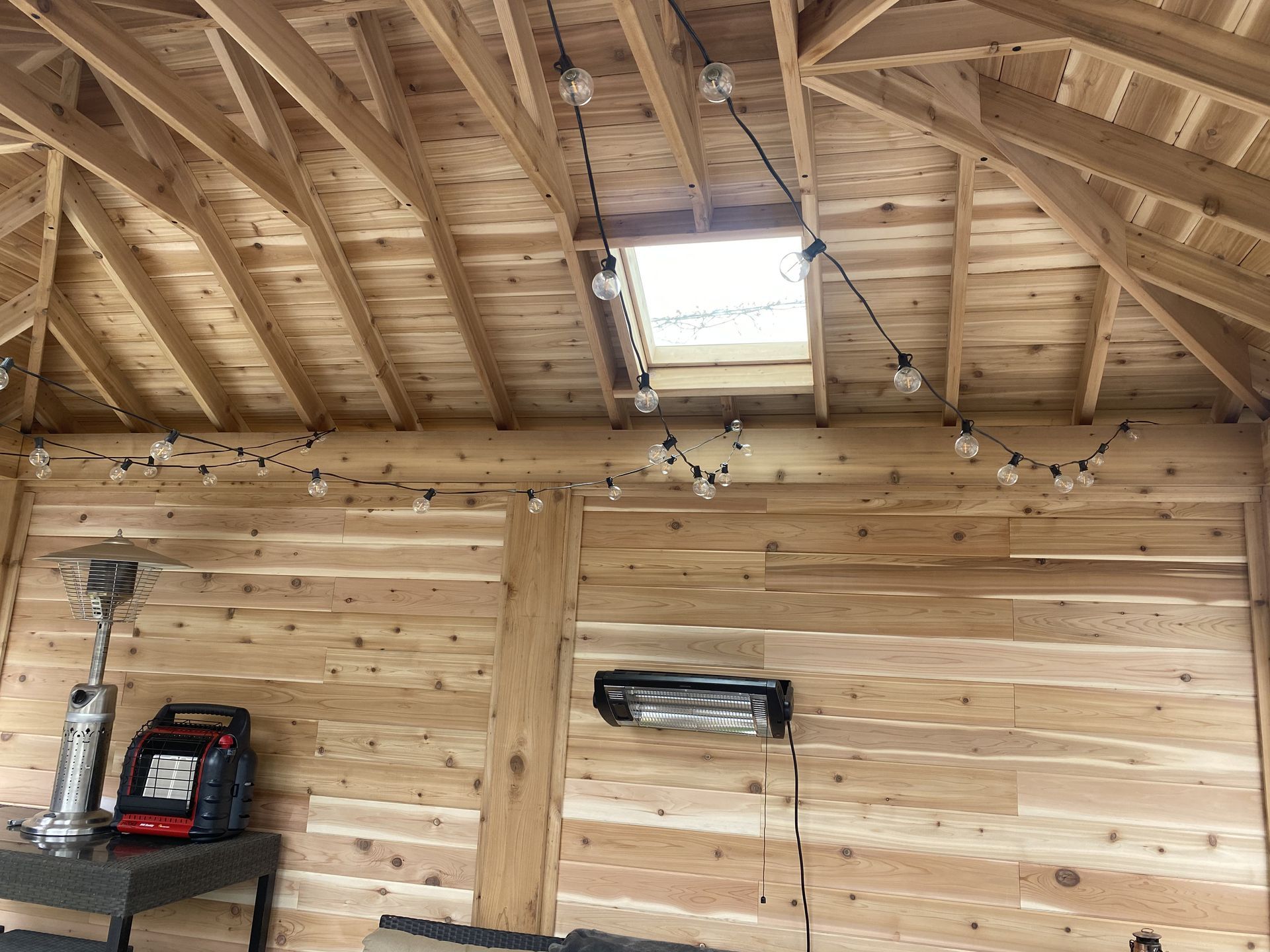 The inside of a wooden building with a skylight and lights hanging from the ceiling.