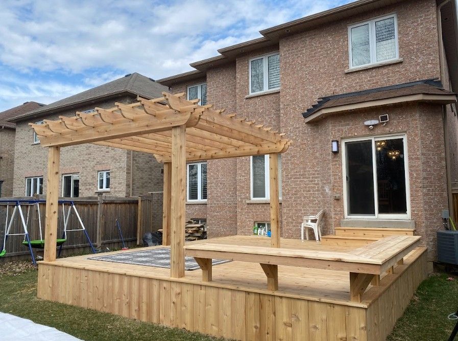 Wooden deck with pergola attached to a brick house. Includes a sliding glass door and windows.