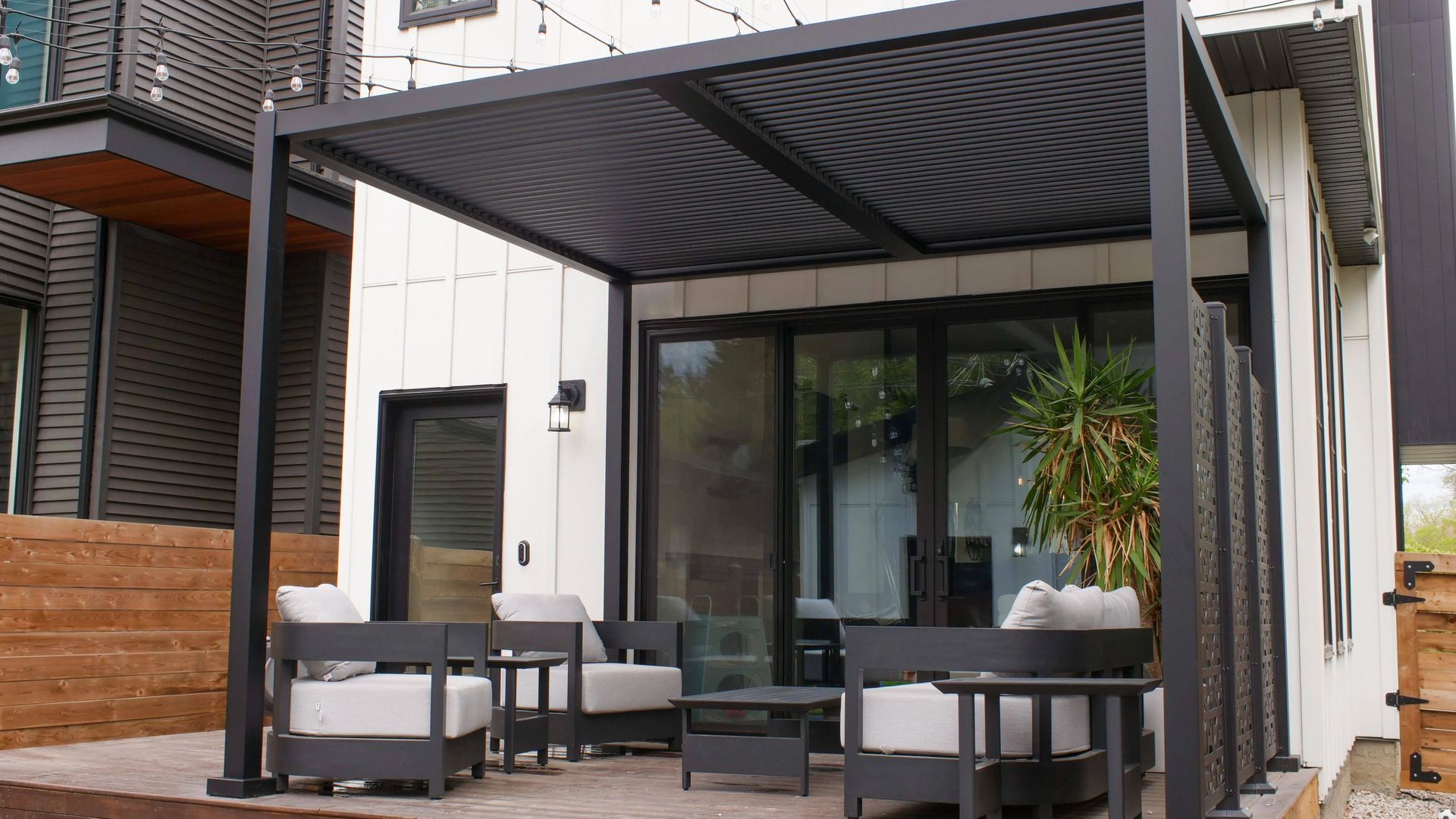 Covered deck with modern furniture outside a contemporary house.