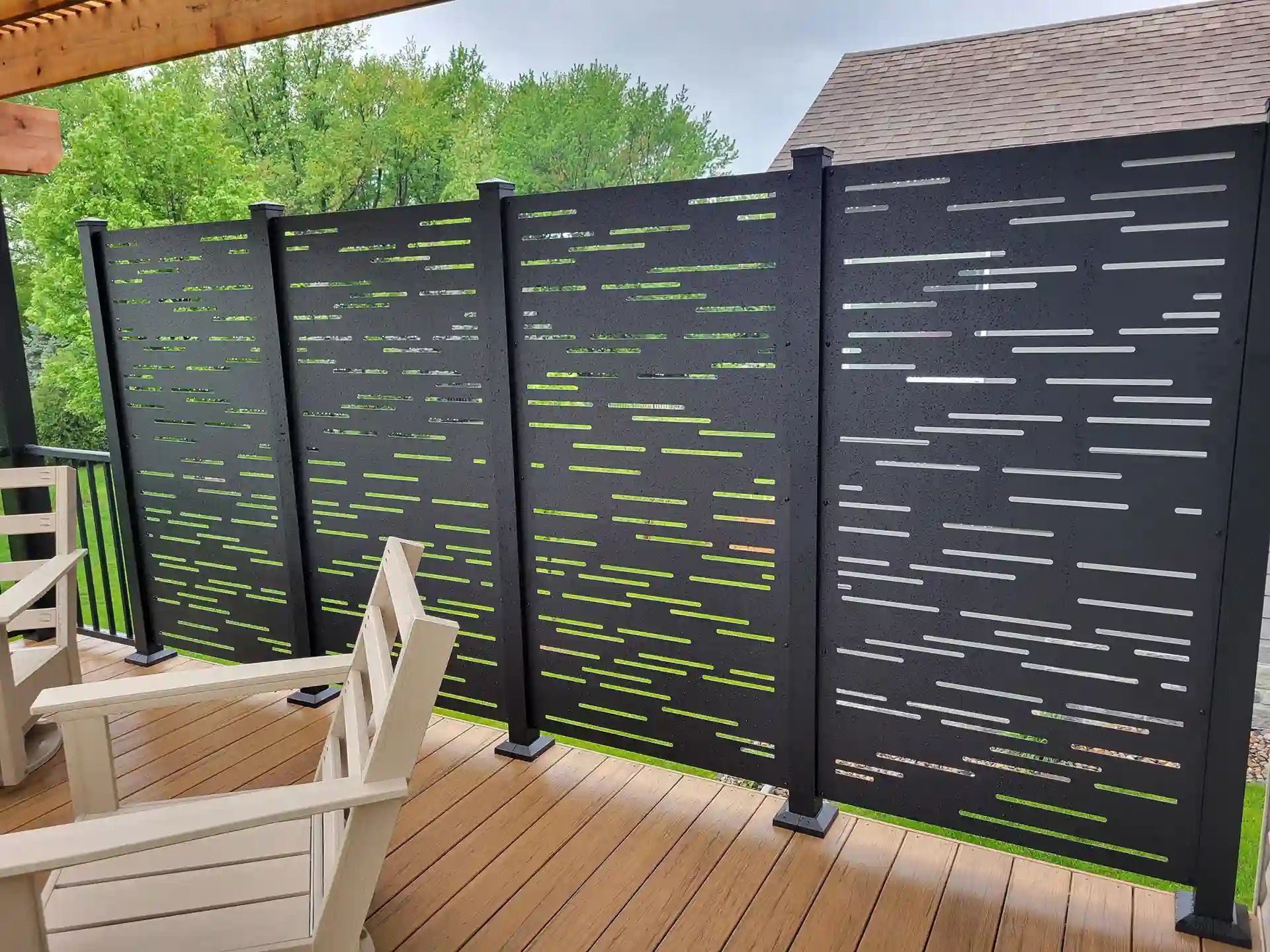 Black privacy screen panels on a deck overlooking green trees.