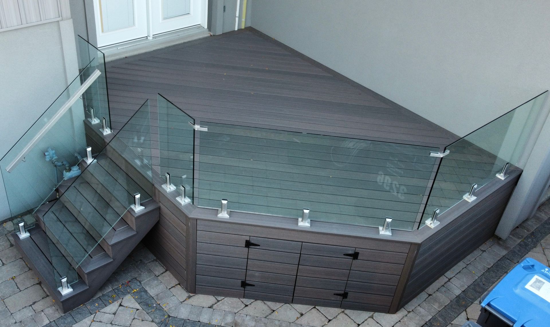 Raised deck with glass railing and built-in storage under stairs.