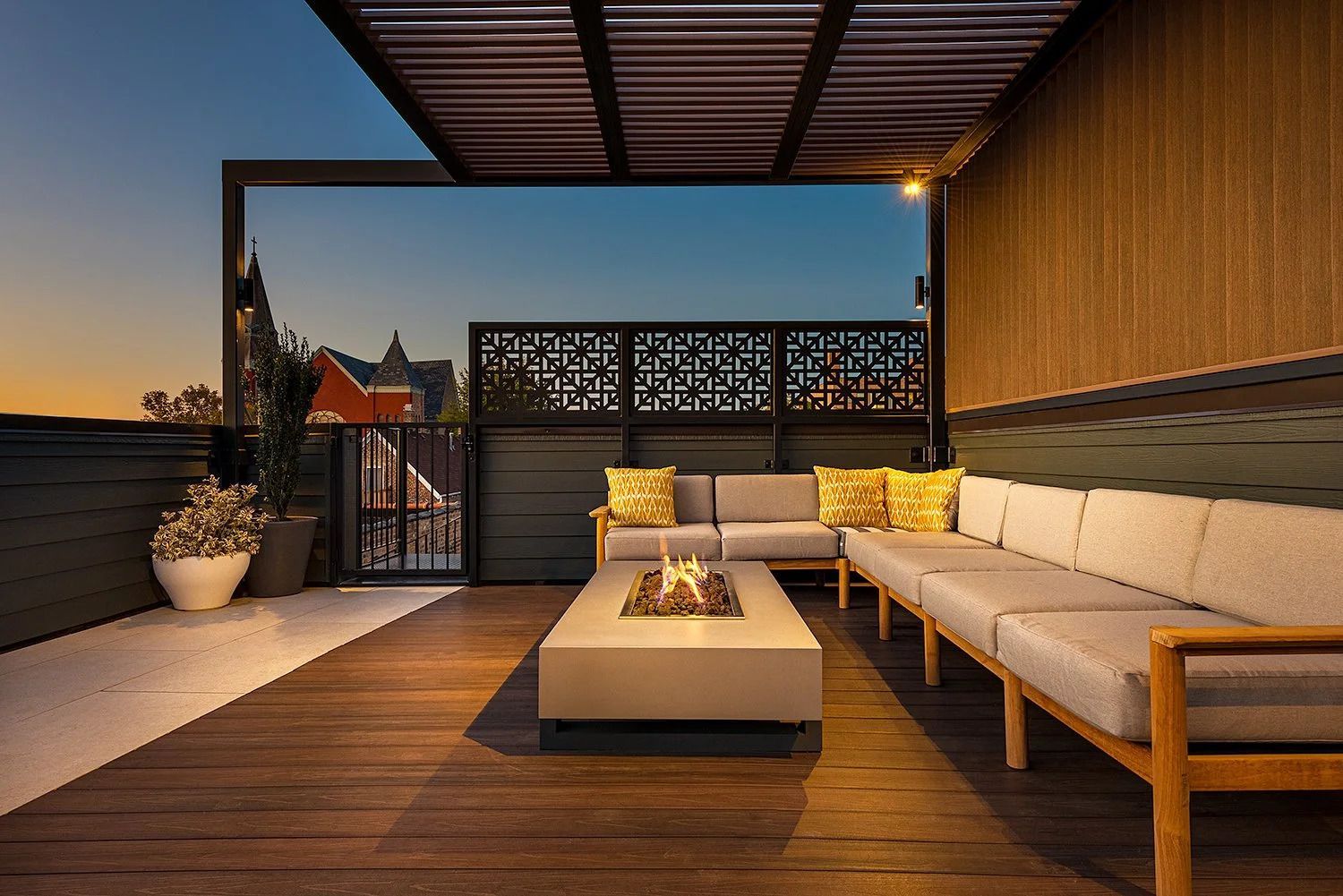 Modern rooftop patio with sectional seating and firepit at sunset.