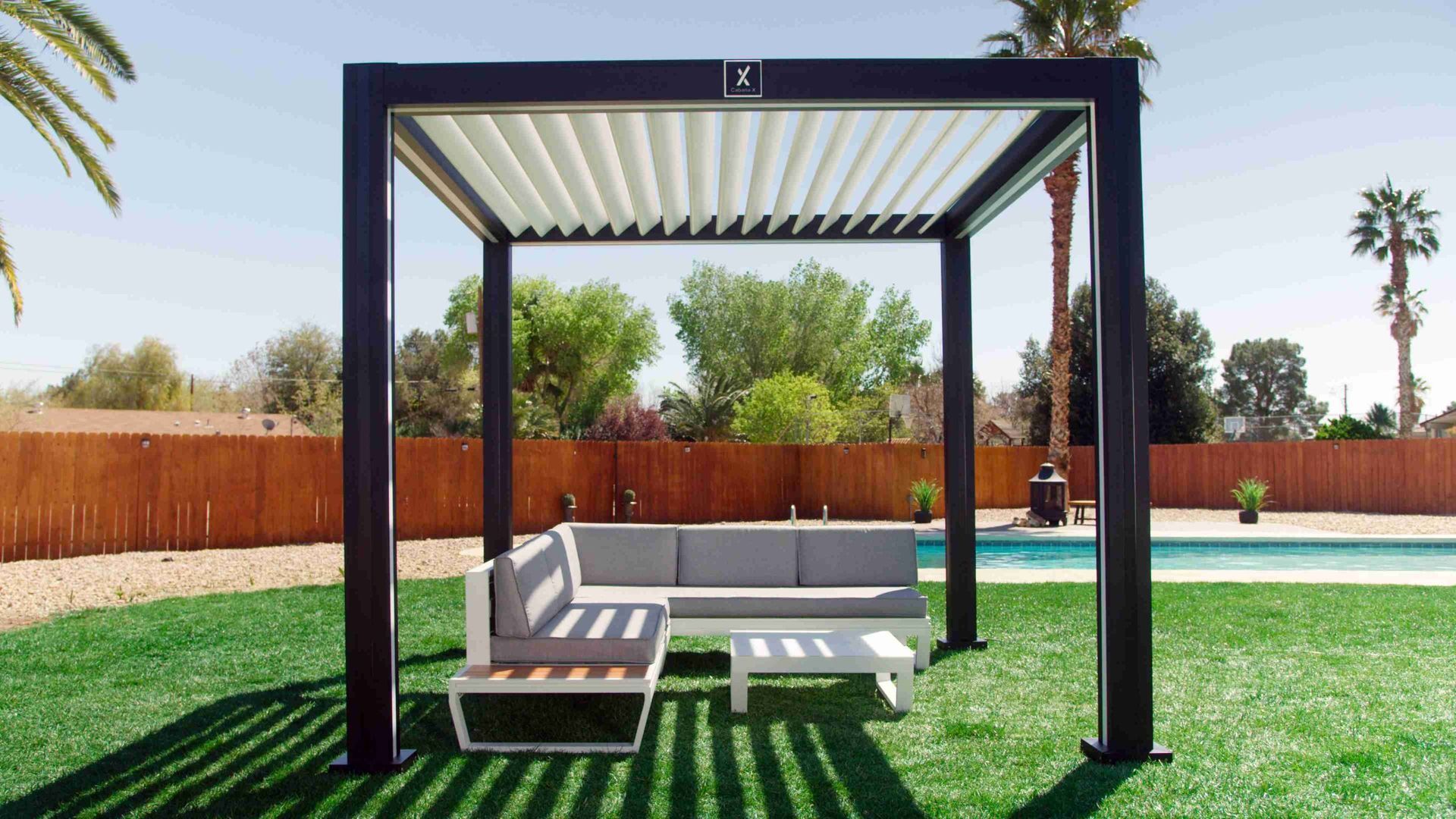 A pergola with a couch and table underneath it in a backyard.