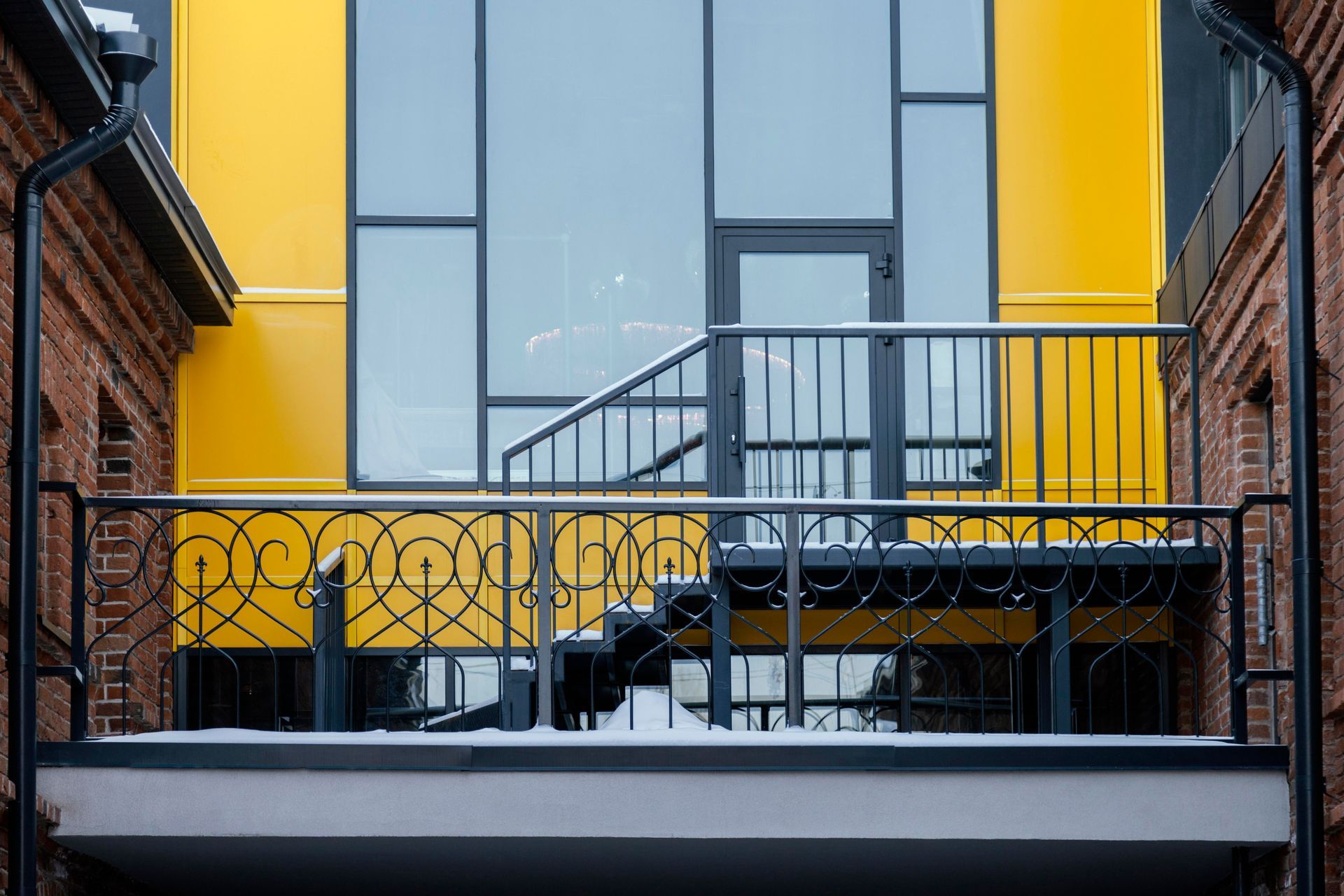 A yellow building with a balcony and stairs in front of it.